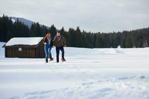 couple having fun and walking in snow shoes photo