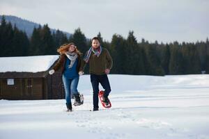 pareja divirtiéndose y caminando con raquetas de nieve foto