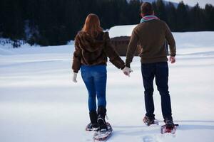 pareja divirtiéndose y caminando con raquetas de nieve foto