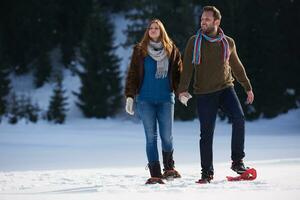 couple having fun and walking in snow shoes photo