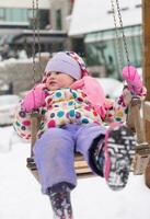 little girl at snowy winter day swing in park photo