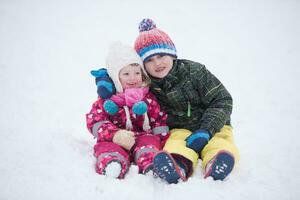 grupo de niños divirtiéndose y jugando juntos en la nieve fresca foto