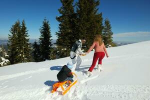 familia divirtiéndose en la nieve fresca en las vacaciones de invierno foto