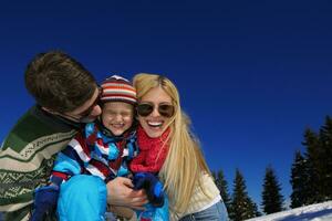 family having fun on fresh snow at winter vacation photo