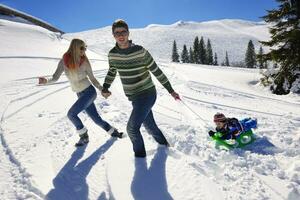 family having fun on fresh snow at winter vacation photo