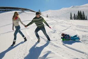 family having fun on fresh snow at winter vacation photo