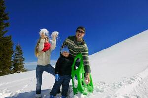 familia divirtiéndose en la nieve fresca en las vacaciones de invierno foto