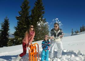 family having fun on fresh snow at winter vacation photo