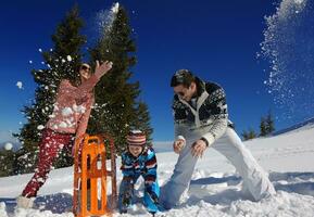 familia divirtiéndose en la nieve fresca en las vacaciones de invierno foto