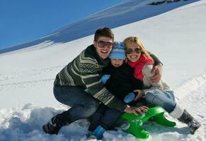 familia divirtiéndose en la nieve fresca en las vacaciones de invierno foto