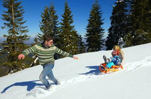 family having fun on fresh snow at winter vacation photo