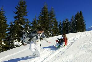 familia divirtiéndose en la nieve fresca en las vacaciones de invierno foto