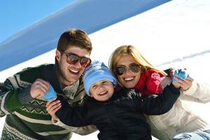 familia divirtiéndose en la nieve fresca en las vacaciones de invierno foto