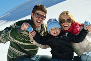 family having fun on fresh snow at winter vacation photo