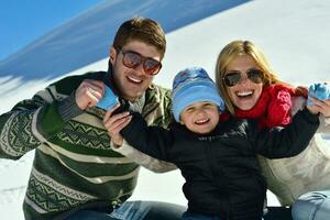 family having fun on fresh snow at winter vacation photo