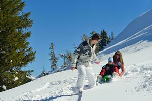 familia divirtiéndose en la nieve fresca en las vacaciones de invierno foto