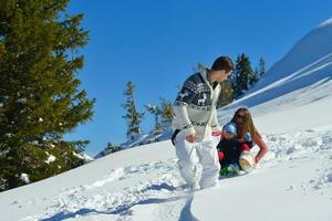 family having fun on fresh snow at winter vacation photo