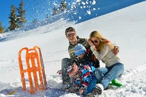 familia divirtiéndose en la nieve fresca en las vacaciones de invierno foto