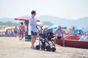 mother walking on beach and push baby carriage photo