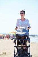 madre caminando en la playa y empujando el carro de bebé foto