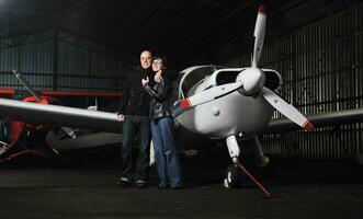 contento joven Pareja posando en frente de privado avión foto