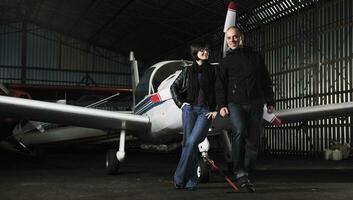 happy young couple posing in front of private airplane photo