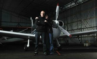 happy young couple posing in front of private airplane photo