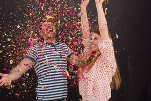 couple blowing confetti in the air isolated over gray photo