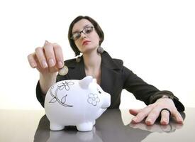 business woman putting money coins in piggy bank photo