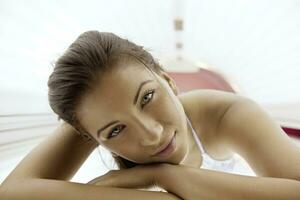 Beautiful young woman tanning in solarium photo