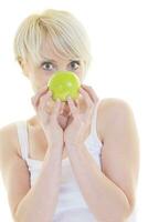una joven feliz come manzana verde aislada en blanco foto