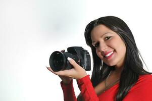 mujer joven sosteniendo una cámara en la mano tomando una foto aislada