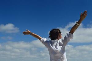 happy young woman with spreading arms to sky photo