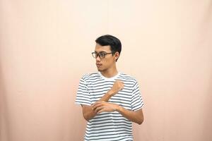 Asian man with glasses wearing casual striped shirt, fist fist pose, indicating strong or ready to fight. Isolated beige background. photo