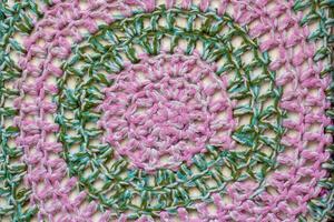 Fabric texture. Knitted circular patterns of pink and green wool. photo