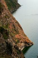 Beautiful red rocks on the shore of Lake Baikal on Olkhon Island. Vertical frame. photo