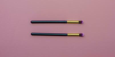 makeup brushes on pink colored composed background. Top view photo