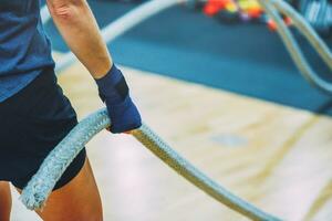 Side view of dedicated caucasian young woman exercising with battle ropes in health club, copy space photo
