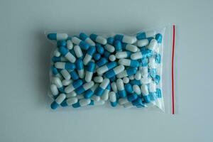 Several white-blue capsules in a ziplock bag against a white background. photo