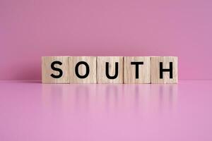 Wooden blocks form the text SOUTH against a pink background. photo