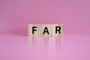 Wooden blocks form the text FAR against a pink background. photo