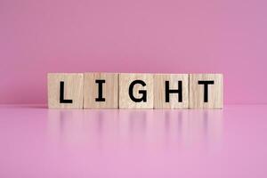Wooden blocks form the text LIGHT against a pink background. photo