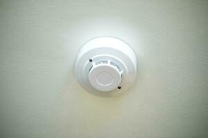 Fire alarm detector on the ceiling with white background. Close-up. photo