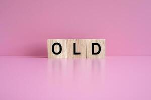 Wooden blocks form the text OLD against a pink background. photo