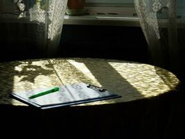 tablet with a piece of paper and a pen on a table with rays of sunshine photo