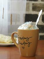 cup of cocoa with foam and colorful sprinkles stands next to a bun on the table photo