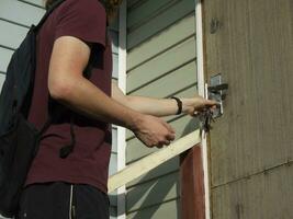 guy in a maroon T-shirt opens the door with a key photo