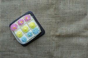 Fresh and delicious bento mini vanilla cupcakes with whipping cream pastel colors. on brown fabric background. Top view with copy space photo