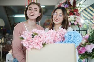 retrato de dos joven hermosa hembra floristas con floral manojo entrega, sonriente y mirando a cámara, encantador negocio emprendedor, flor tienda contento trabajar, brillantemente vistoso flora ramo de flores almacenar. foto