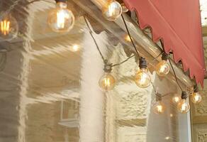 Decorative garland of retro light bulbs hangs on the facade of a street cafe photo